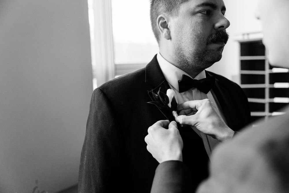 Profile view sequence showing a man adjusting his tie and jacket in black and white.