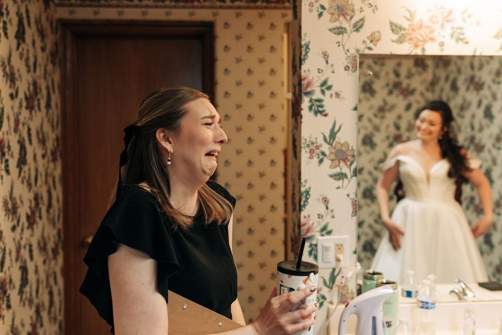 Joyful moment captured in a room with floral wallpaper during wedding preparations.