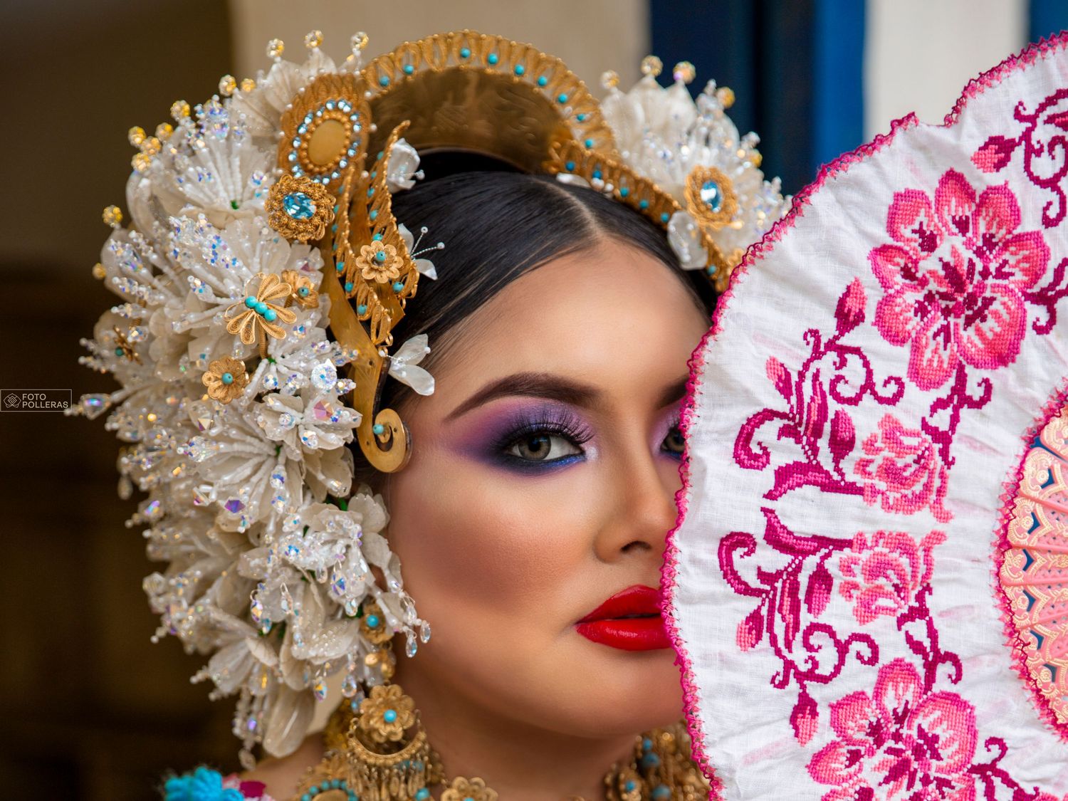 Mujer panameña con maquillaje ataviada con tembleques de la pollera panameña, sosteniendo un abanico de labor a juego con la pollera de gala
