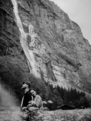 Emotional couple shoot in the Swiss Alps under a waterfall — cinematic black and white portrait by destination wedding photographer