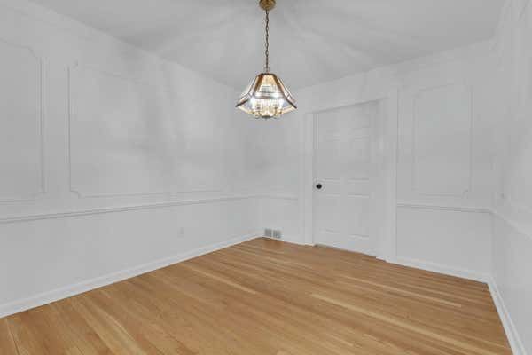 Elegant dining room with light hardwood floors, decorative wall molding, and modern geometric chandelier.