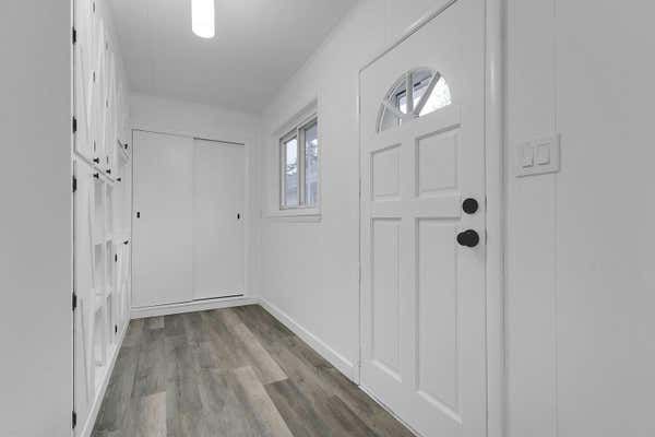 Entryway with white front door featuring oval glass insert, closet, wood floors, and natural light.