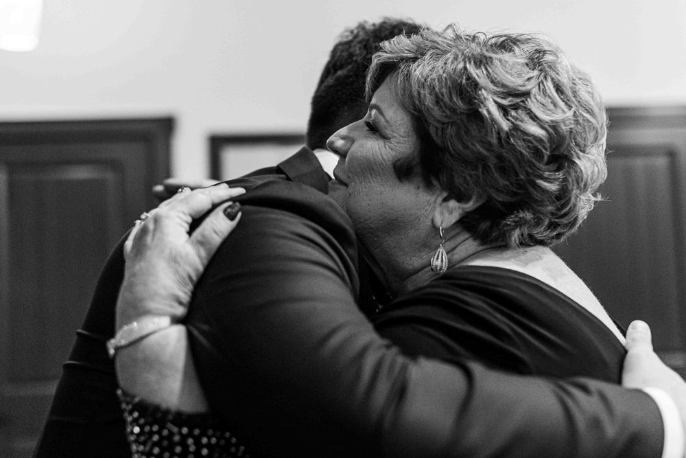 Black and white image of two people sharing an emotional embrace. Groom and his mother.