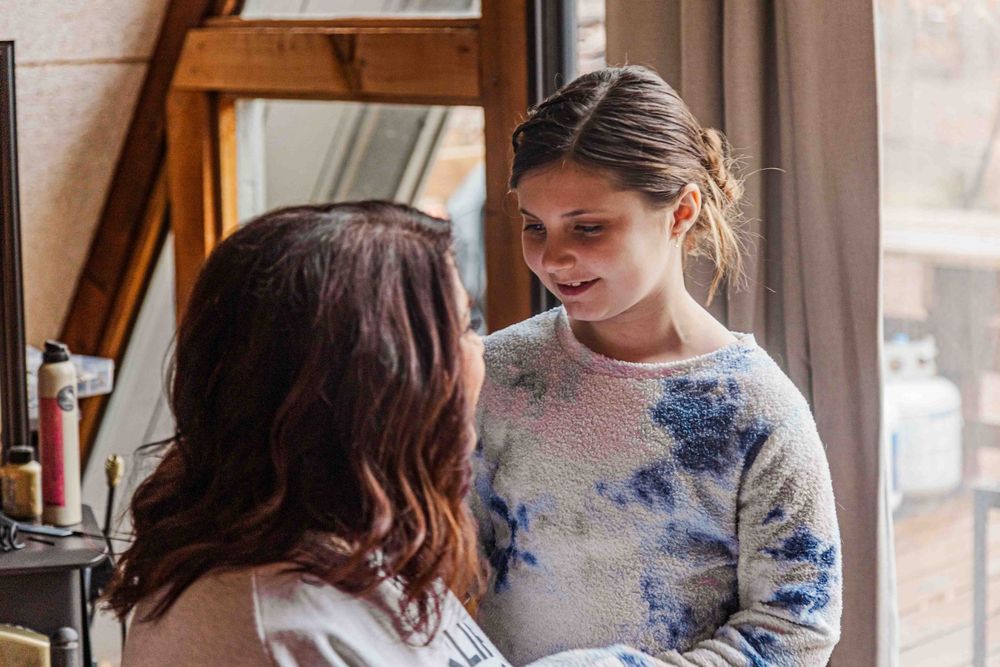 Grandmother and granddaughter smiling at each other while getting ready for wedding ceremony.