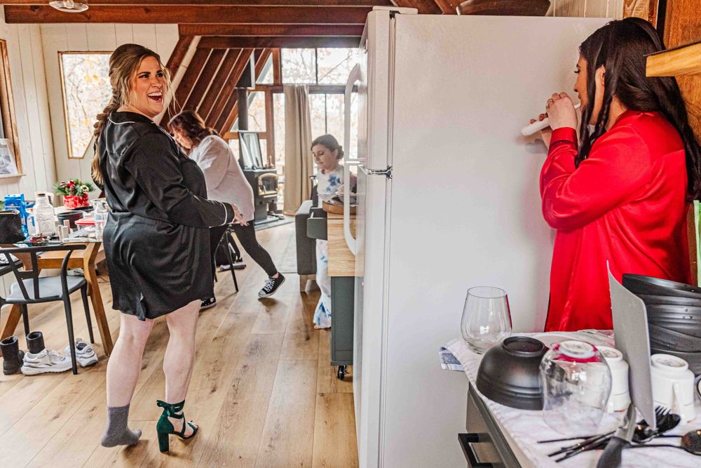 Two people getting ready in a bright room with a red dress visible.