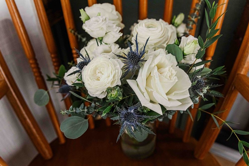 Beautiful white roses and greenery arranged in a classic bouquet on wooden chair.