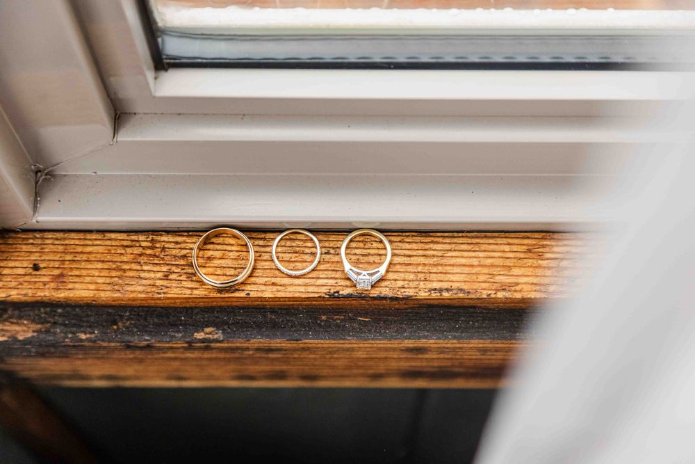 Three wedding rings arranged artistically on a wooden windowsill.