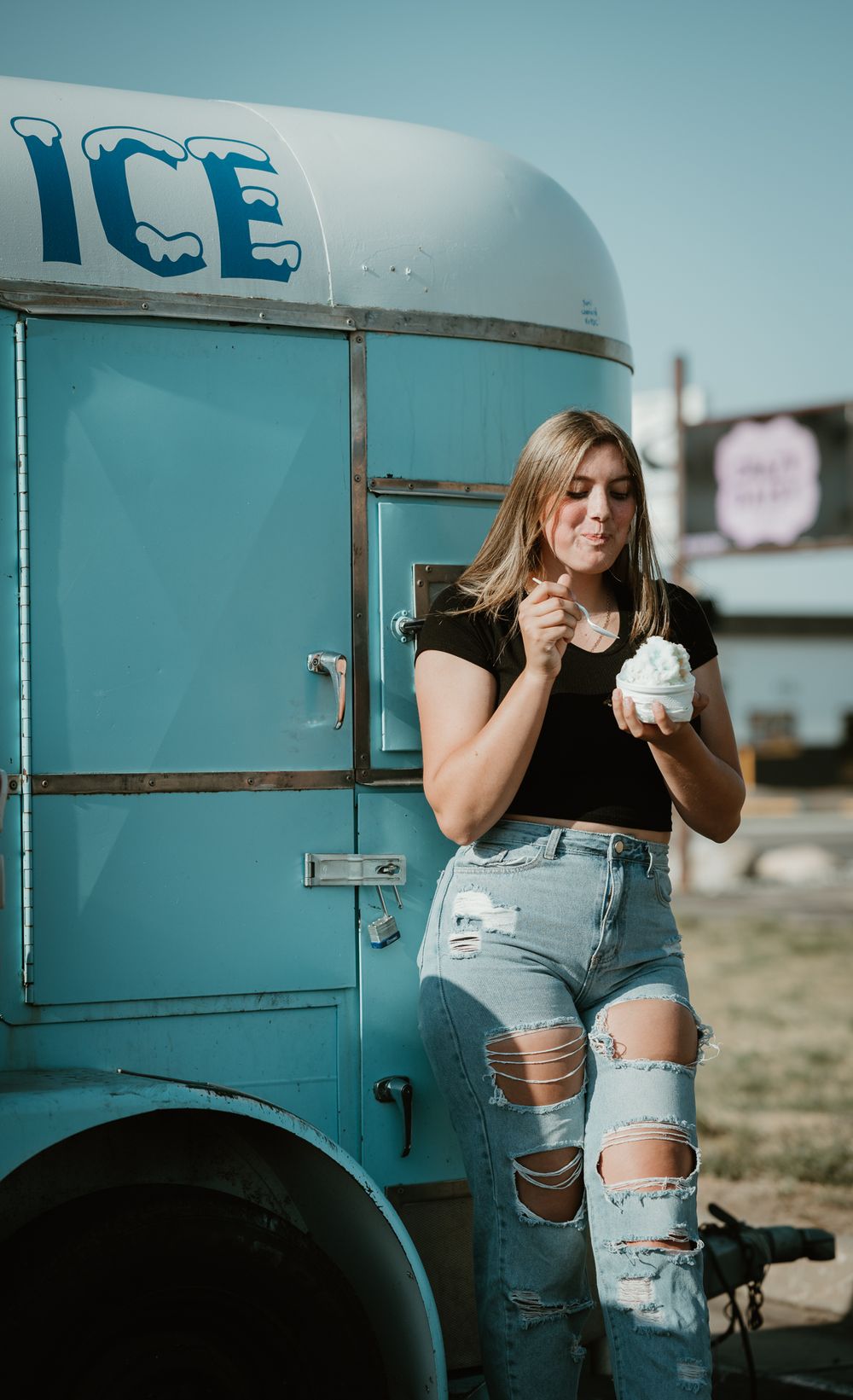 Candid moments captured against turquoise vintage ice truck in casual summer outfit.