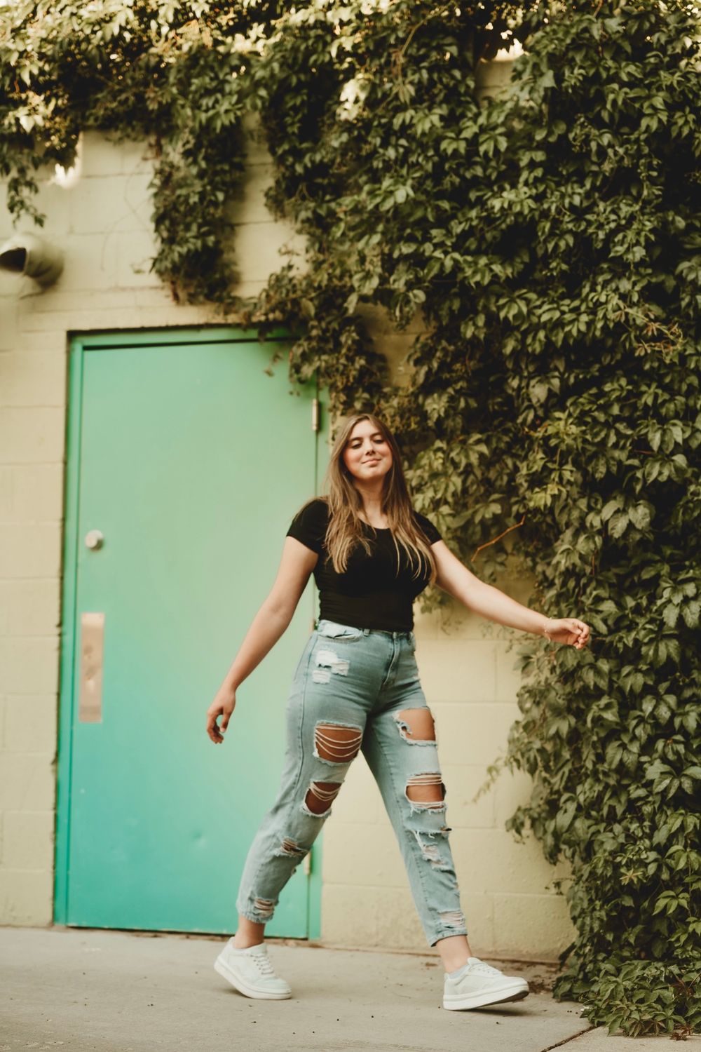 Dynamic fashion poses against ivy wall and turquoise door showing casual street style.