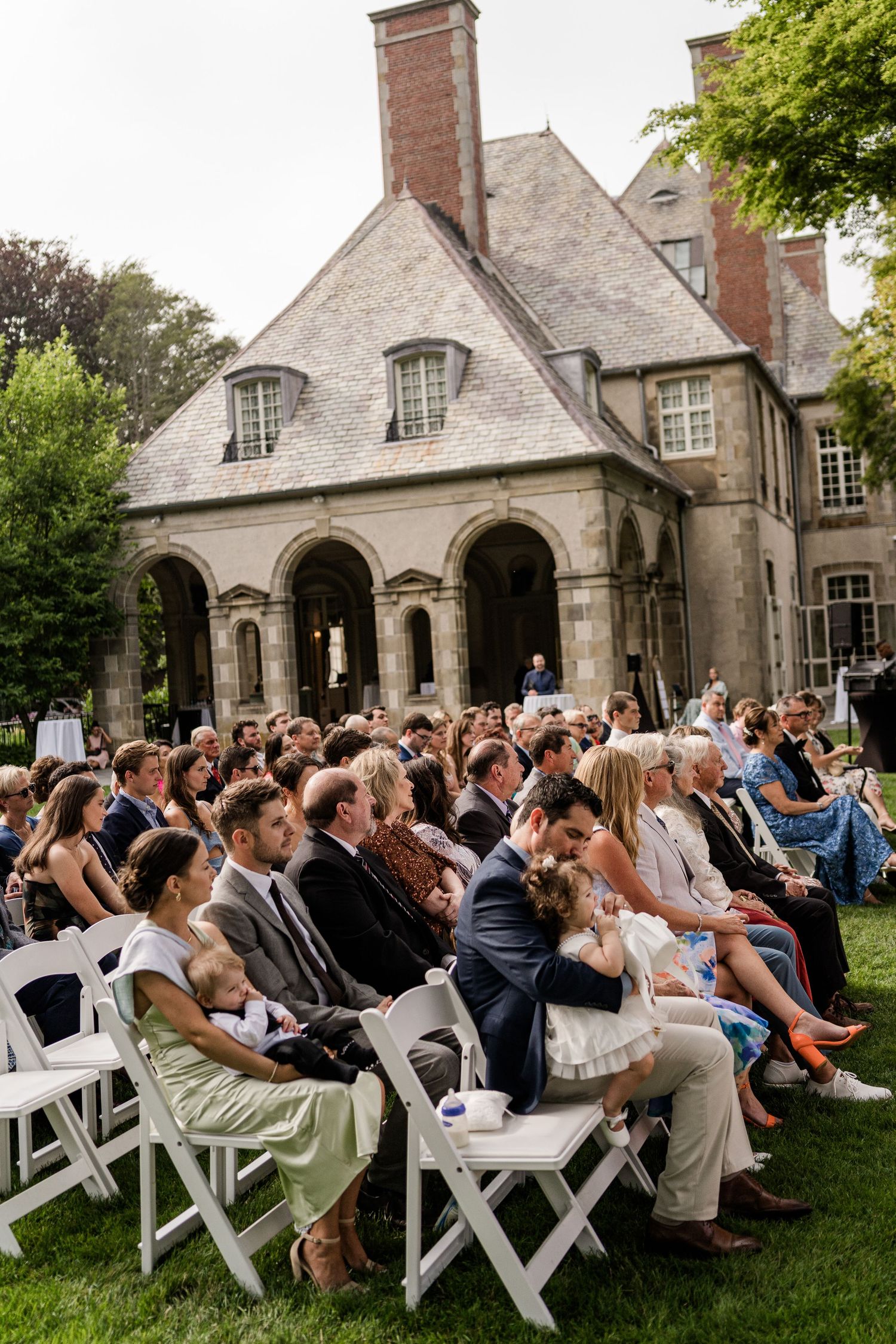 Wedding ceremony guests seated in rows with bridesmaids holding white floral bouquets.