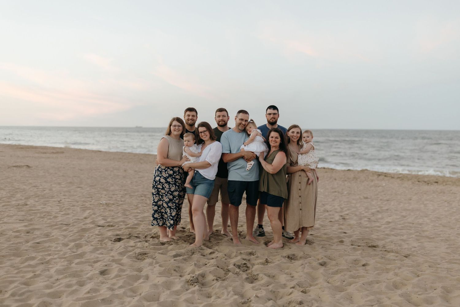 Group photo of friends gathered together on beach at sunset.