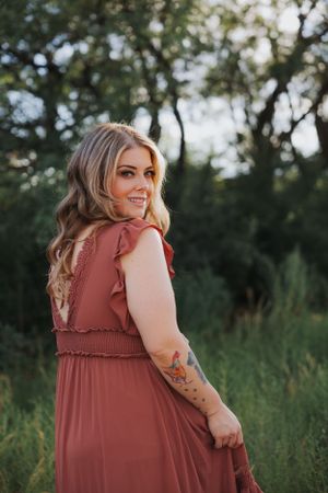 A candid outdoor portrait showcasing a rust-colored dress with ruffle details.