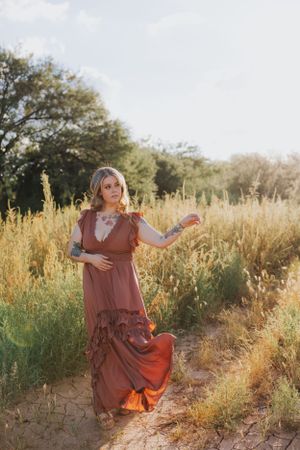 A whimsical outdoor portrait with a flowing rust dress catching movement in golden light.
