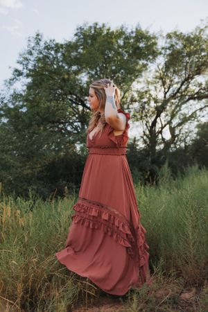 A flowing maxi dress with ruffled details photographed against a natural landscape at sunset.