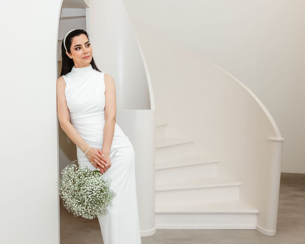Modern bridal portrait against curved white staircase with baby's breath bouquet.