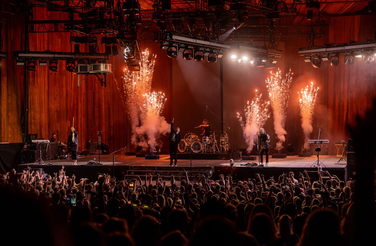 Concert stage performance with dramatic pyrotechnic effects lighting up the venue.