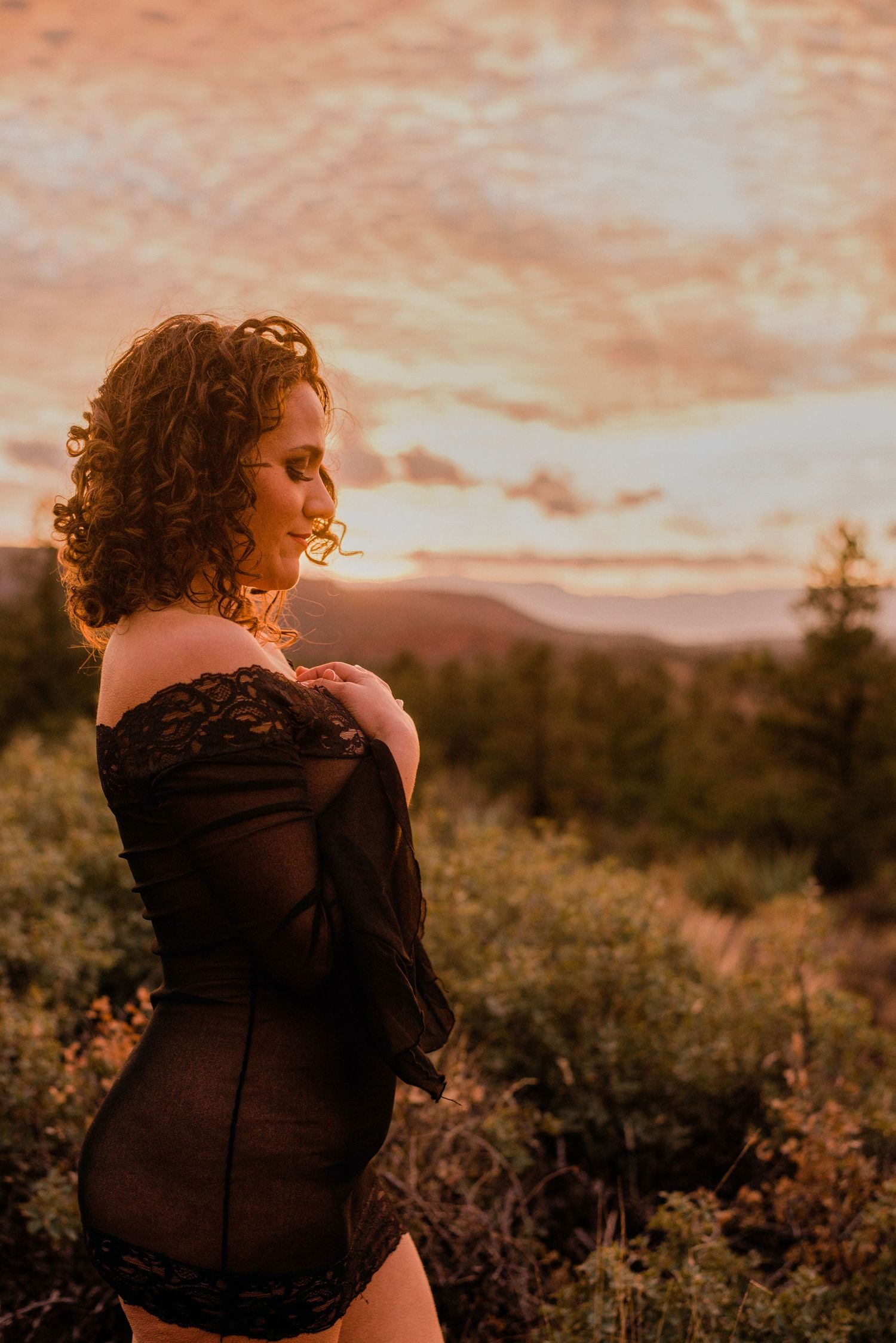 Silhouette in black lace against desert sunset with mountains in background.