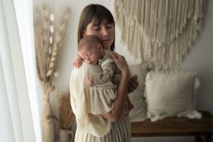 Giovane mamma tiene sulla spalla il suo bimbo di un mese che dorme sereno