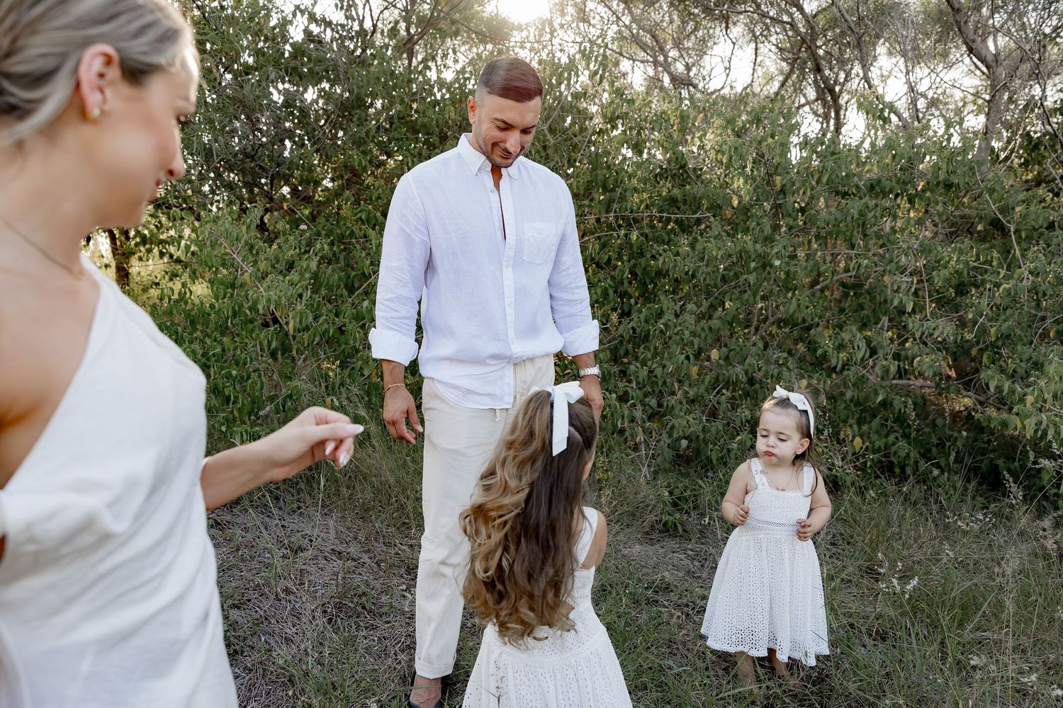 People in coordinated white outfits share joyful moments in a natural outdoor setting.