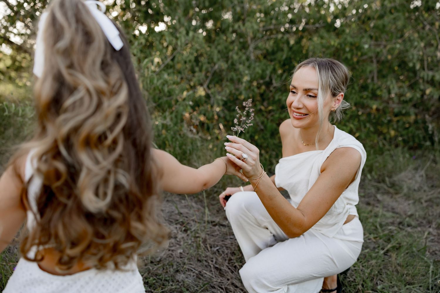 White-clothed family laughs and plays together among wild grasses at sunset.