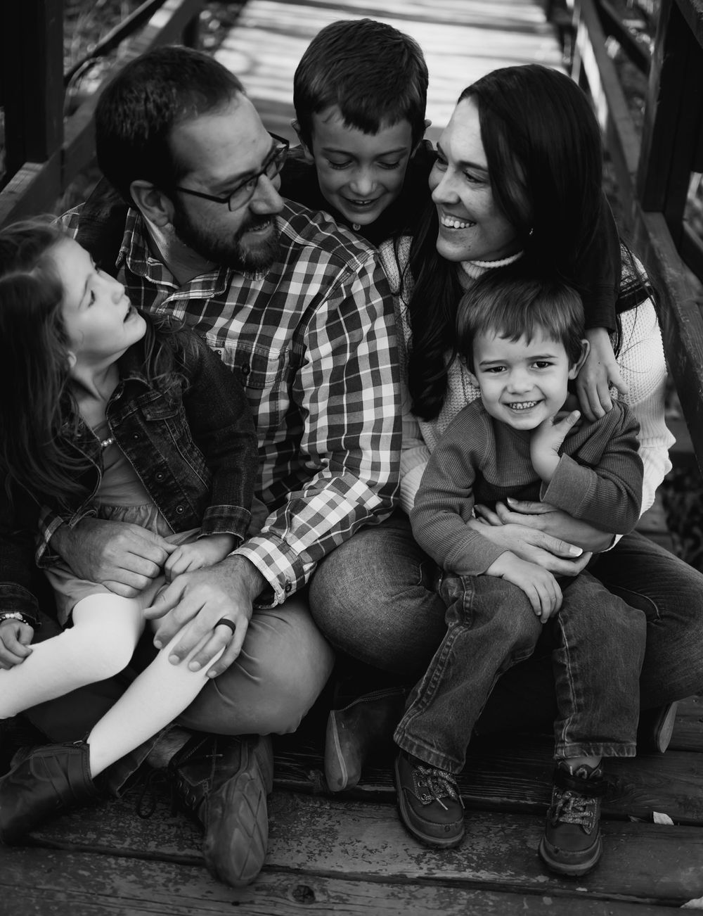 Black and white family portrait showing parents and children sharing joyful moment together.