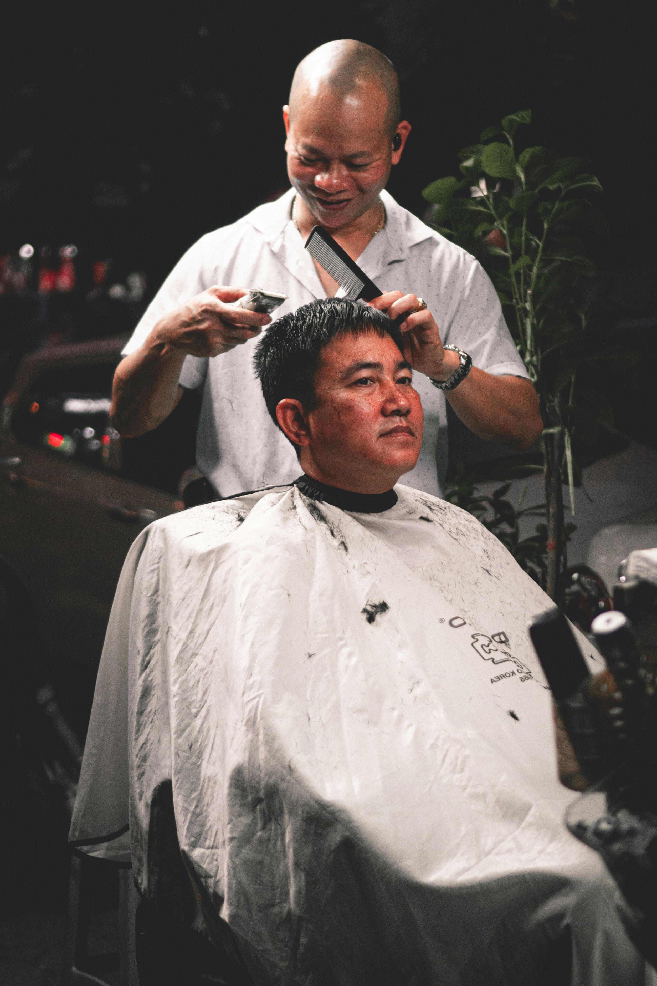 Professional barber giving a haircut in a dimly lit salon setting.