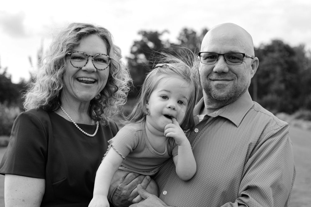Black and white portrait of grandparents with their young grandchild outside.