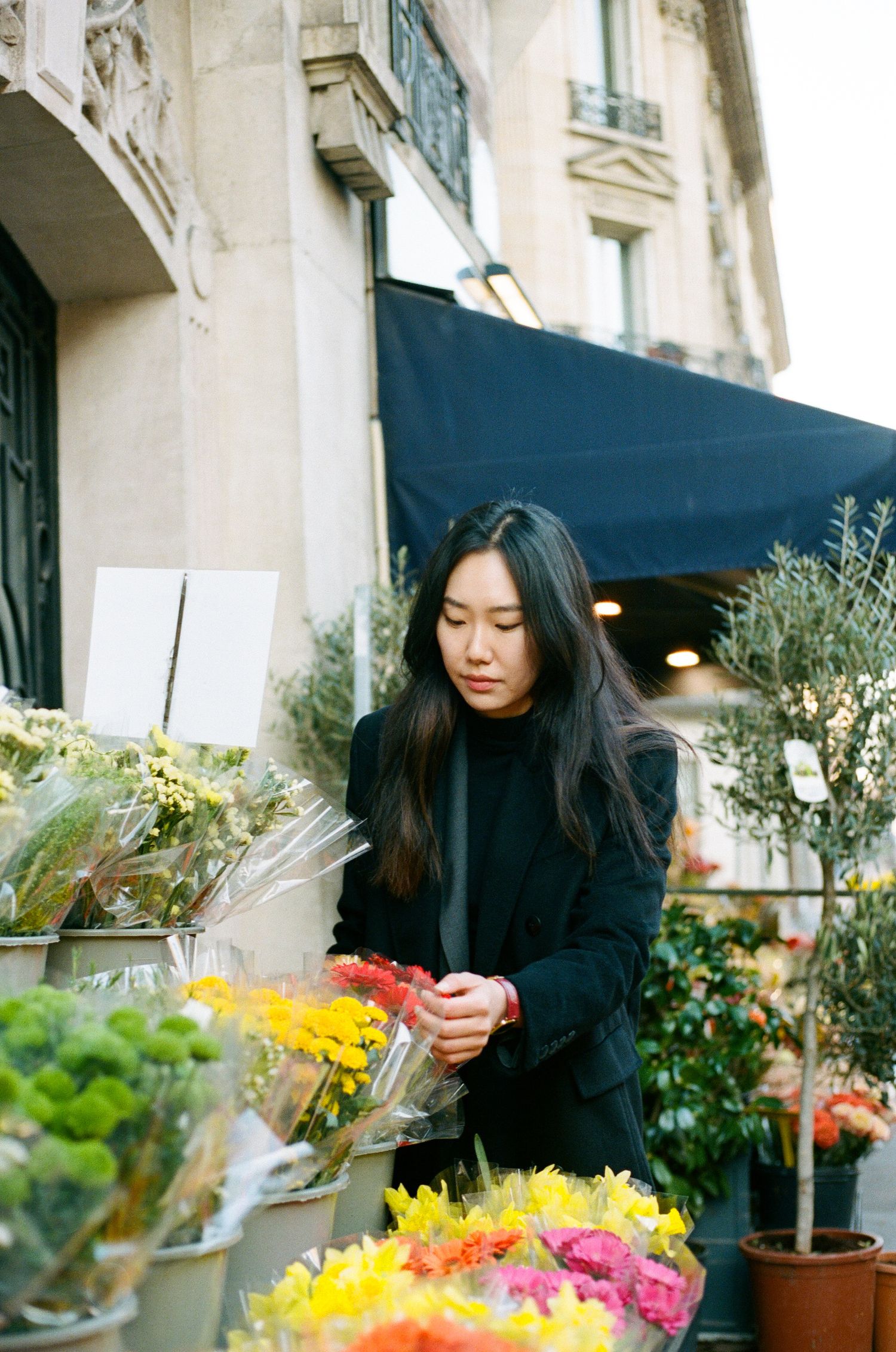 A customer shops for flowers at an outdoor florist stand with colorful bouquets in Paris.