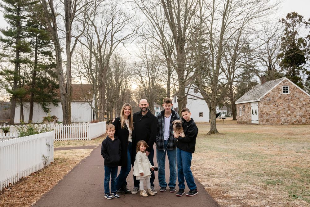 Multi-generational family group poses together on path with stone building in background.