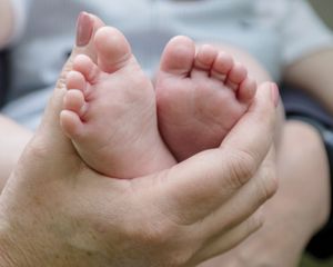 Close up of tiny baby feet being held in adult hands.