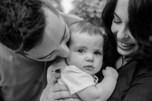 Black and white portrait of parents with baby in intimate moment.