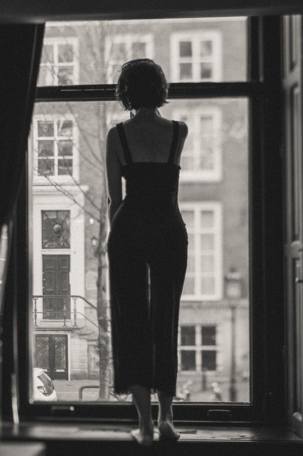 Silhouette of person standing by window in Amsterdam building.