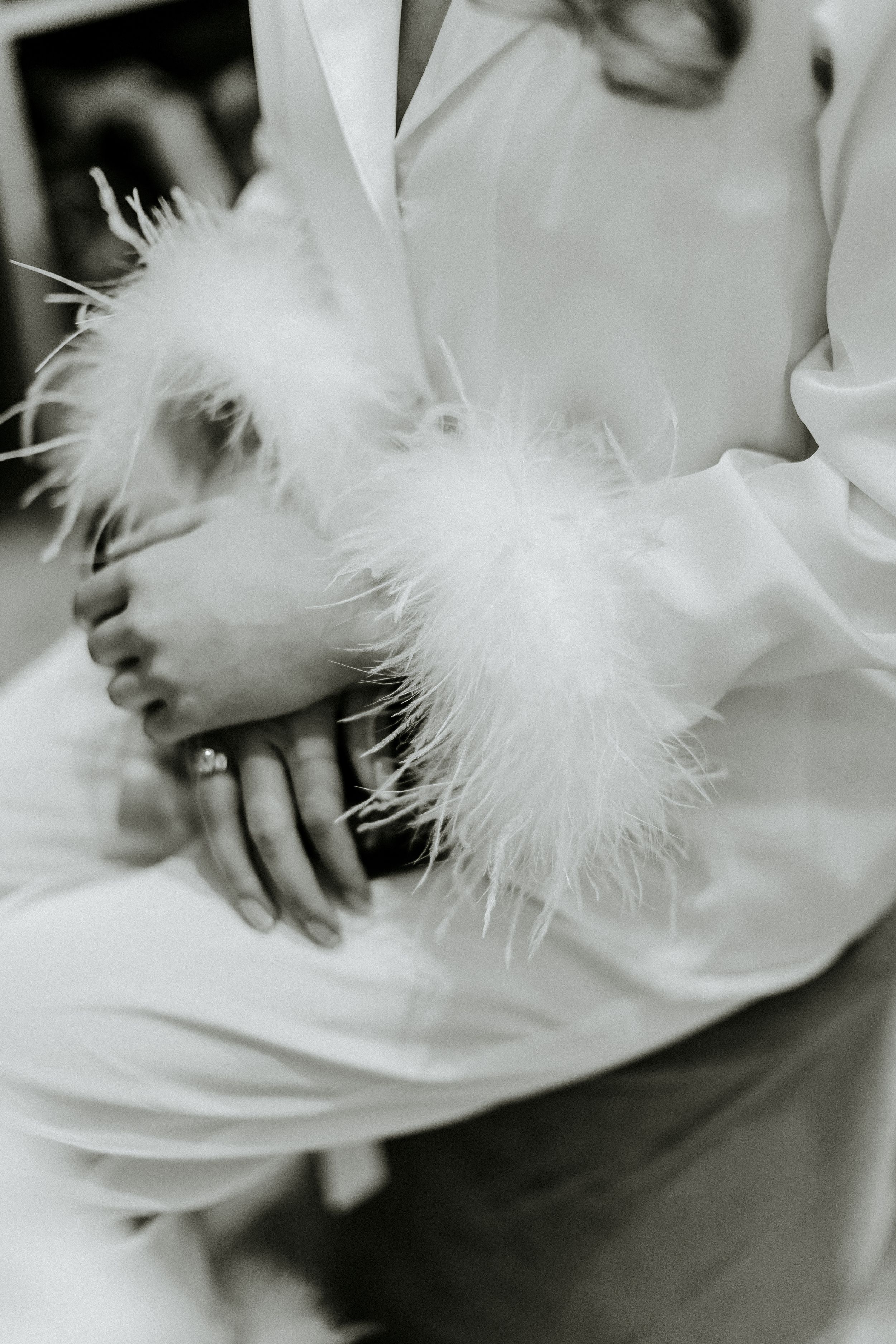 Close-up of white feathered sleeve detail on elegant bridal attire.