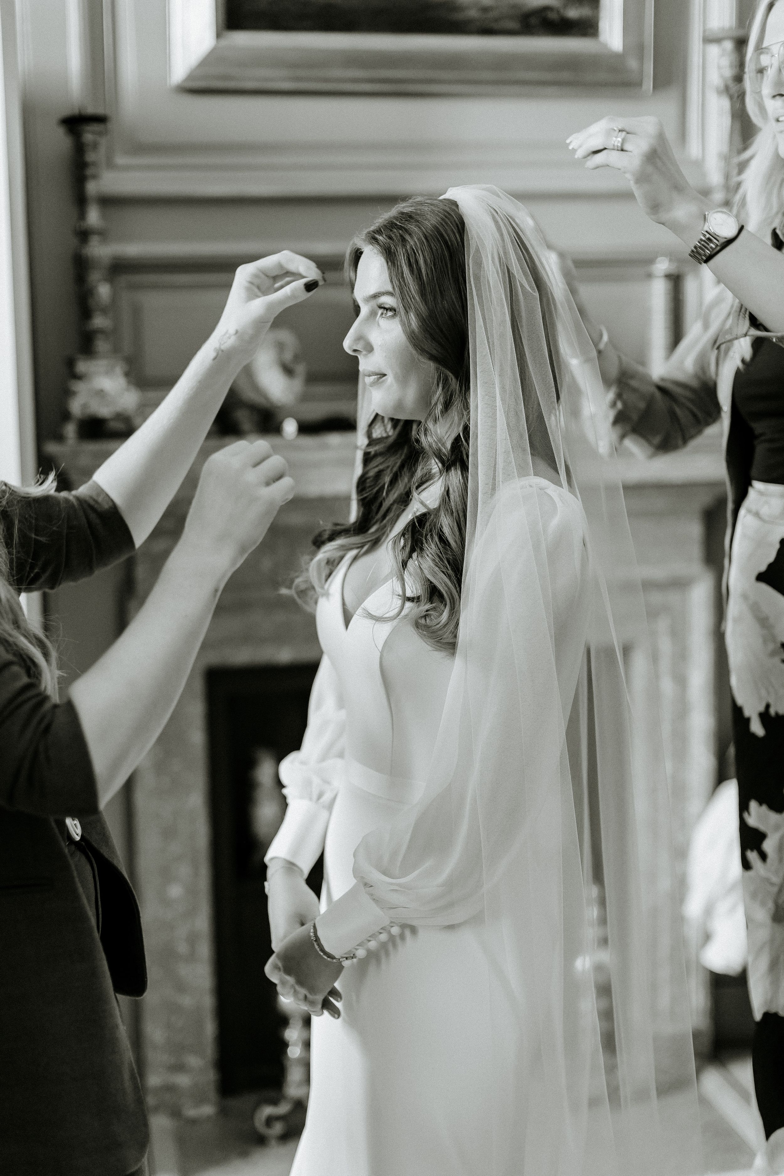 Black and white photo of final bridal preparations with flowing veil.