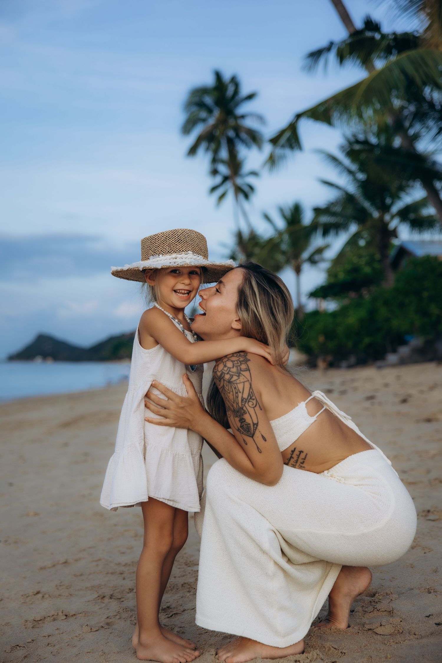 A tender moment shared between two people on a tropical beach with palm trees and ocean in the background.