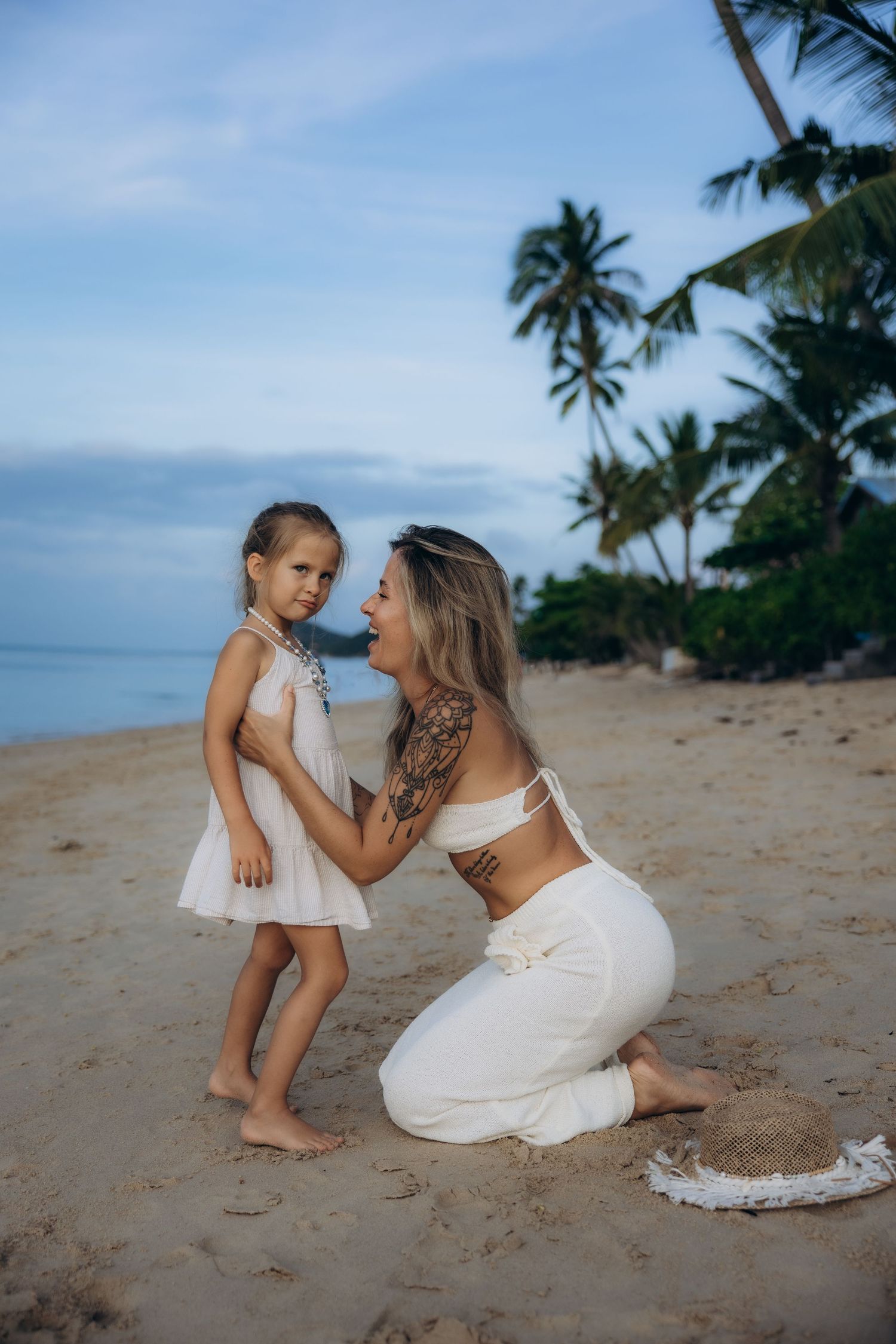 A tender beach moment at sunset with palm trees swaying in the background along a tropical shoreline.
