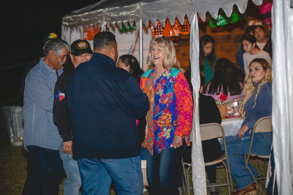 Guests mingling under a white tent at an evening outdoor social event.