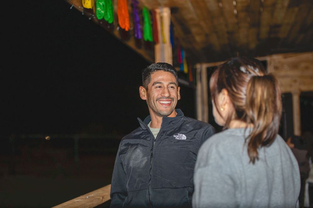 People gathered at a rustic venue with wooden walls and ambient lighting for a social event.