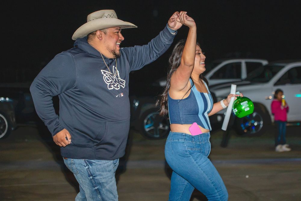 Couples dancing at a western-themed event in a dimly lit venue.