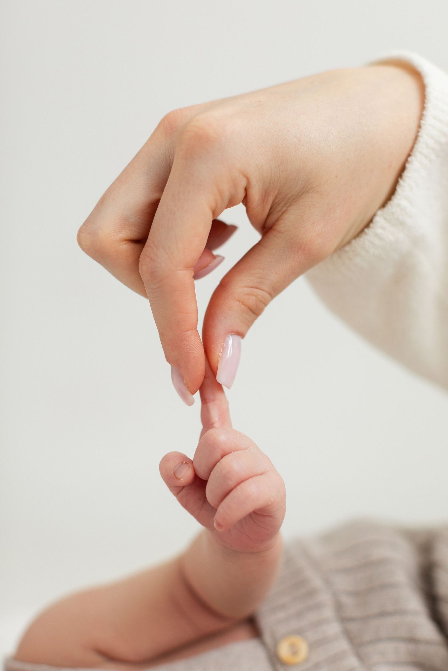 Newborn baby grasping mother's finger in a tender close-up bonding moment.