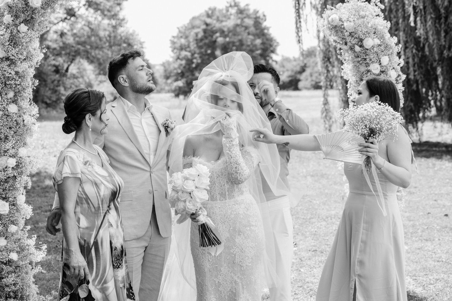 Wedding party in an outdoor setting sharing joyful laughter together in black and white photography.
