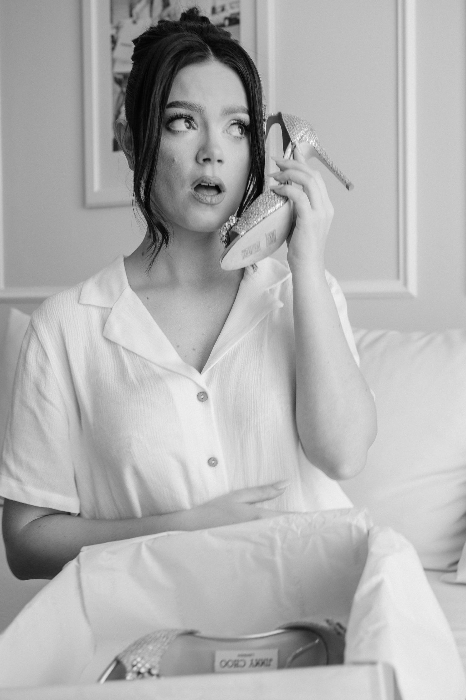 A black and white portrait of someone in white attire talking on a phone with a surprised expression.