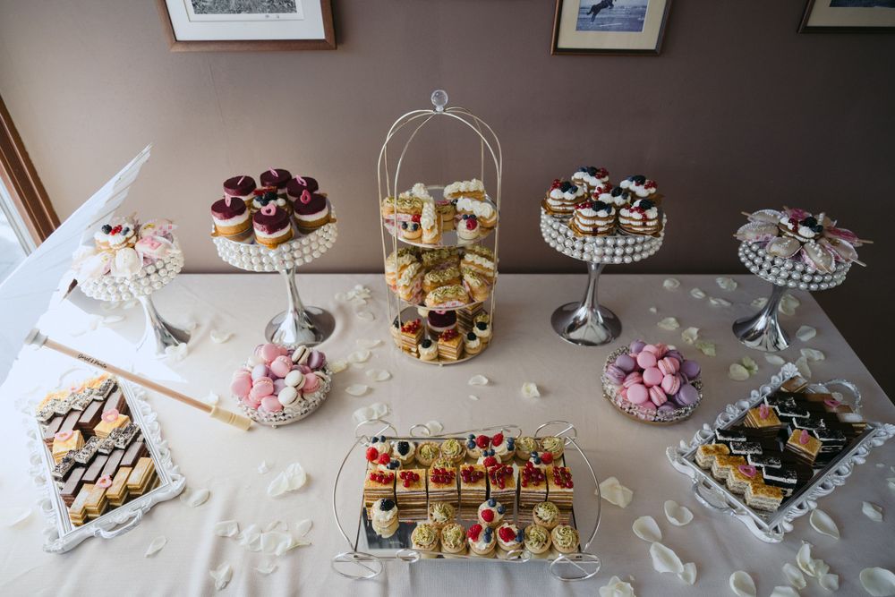 Elegant dessert table with crystal cake stands displays an assortment of pastries, cupcakes, and bite-sized treats.