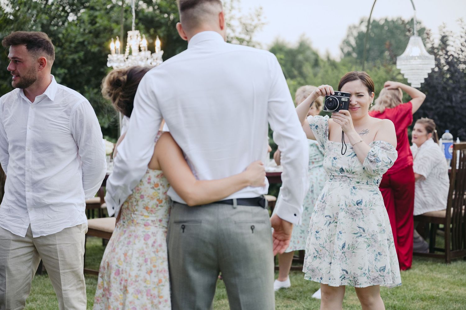 Guests in summer attire mingling and dancing at an outdoor garden party celebration.