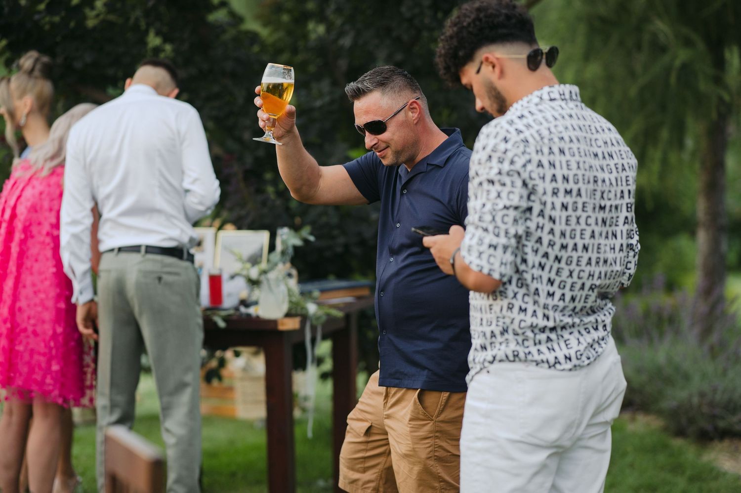 People enjoying drinks at an outdoor party with casual summer attire.