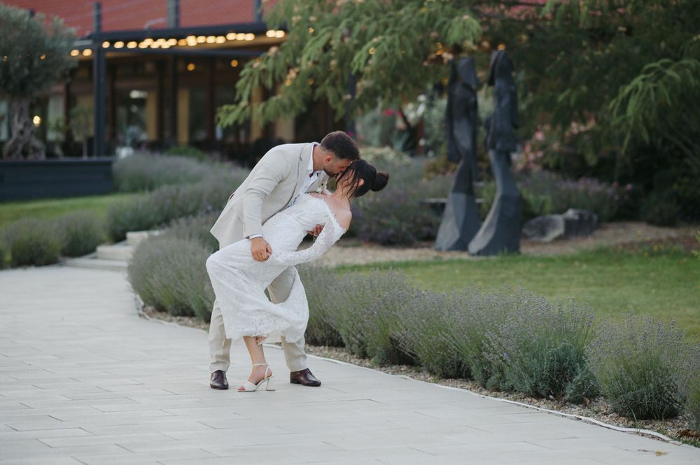 A tender moment between parent and child in white outfits on a garden path during sunset.