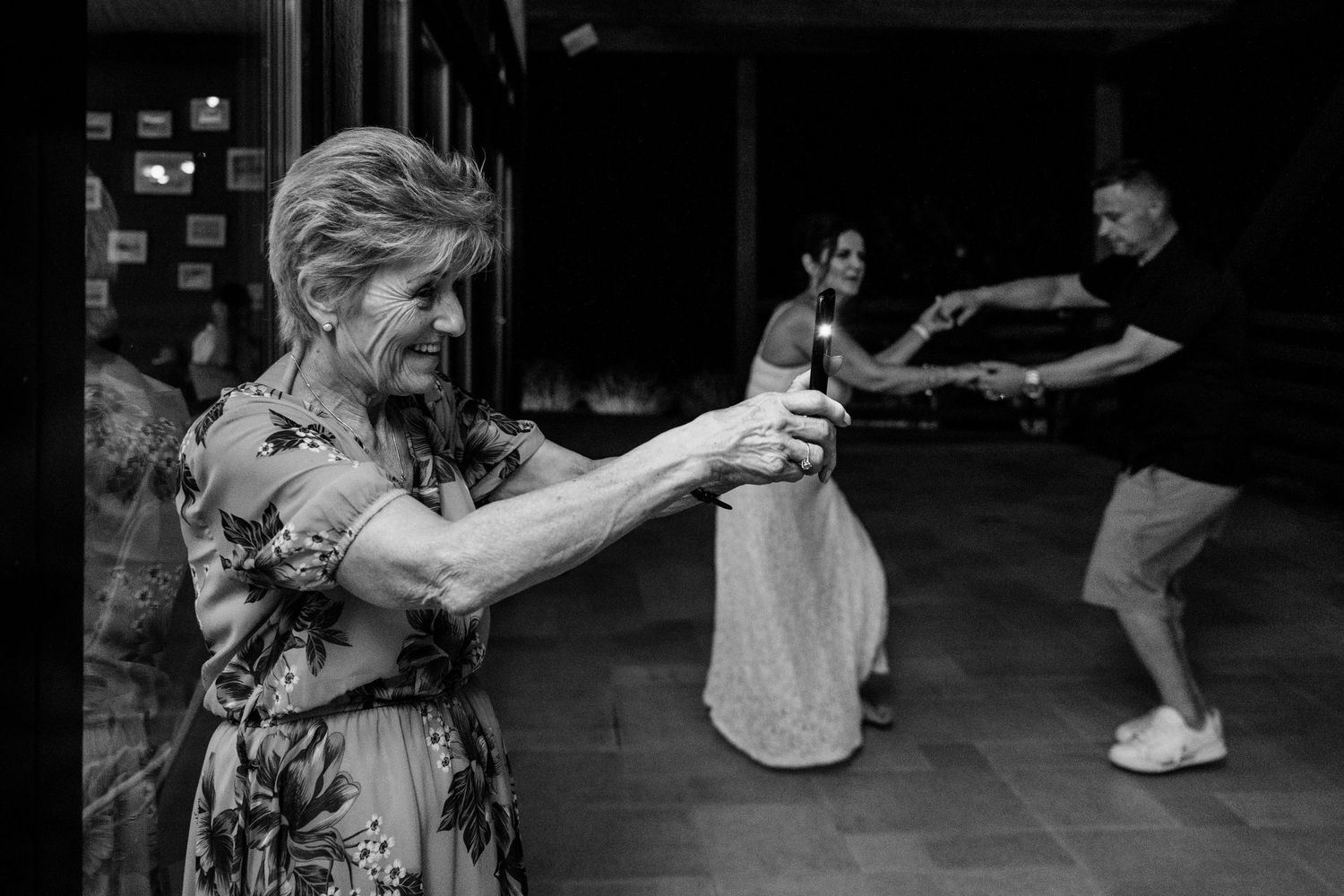 A black and white photograph of people dancing together in a social setting with blurred motion.