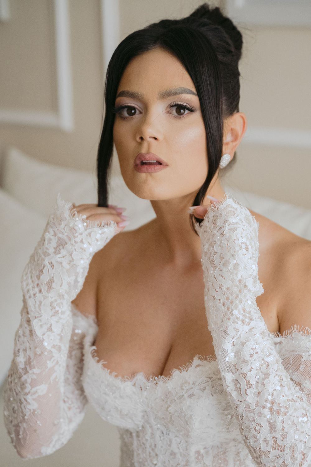 Bride in delicate white lace long-sleeve wedding dress with sweetheart neckline poses elegantly.