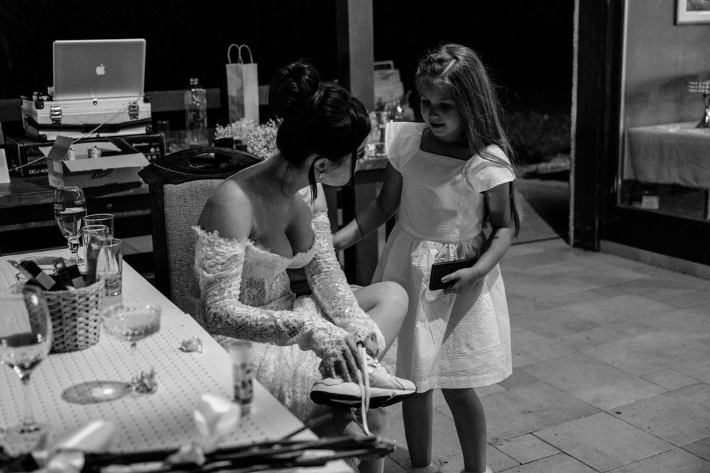 Two people in formal attire prepare together during wedding day moments in black and white photography.