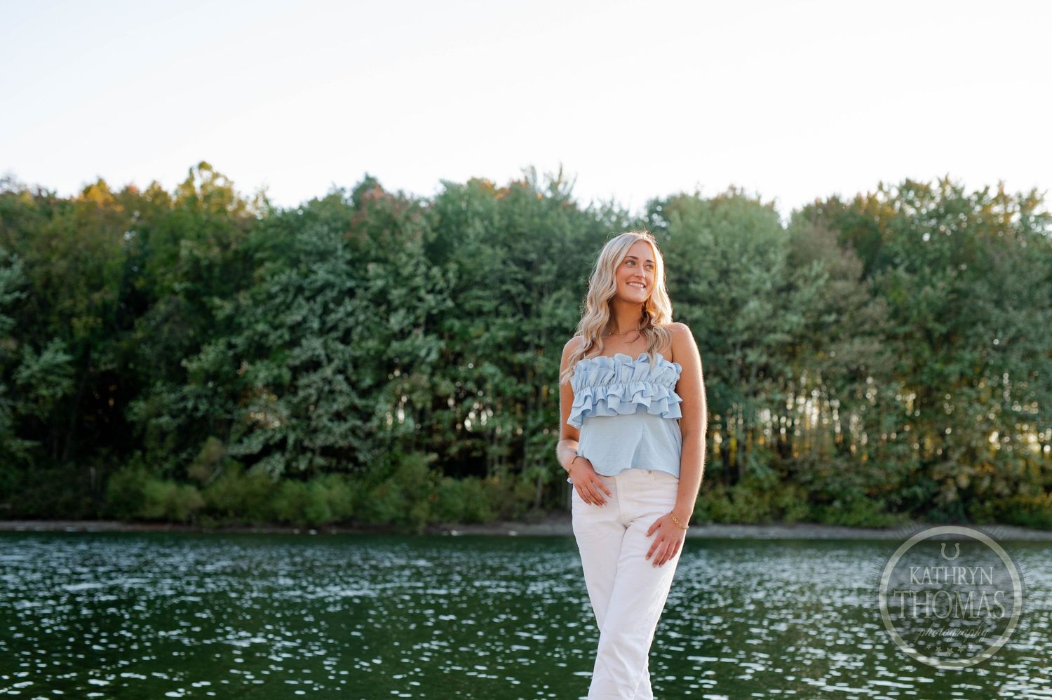 Scenic lakeside portrait with forest background and golden hour lighting.